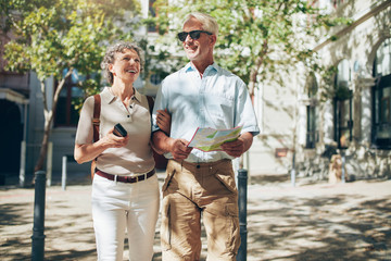 Senior couple with a map walking in the town.