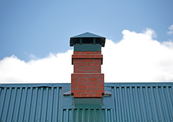 Brick chimney on the green metal roof