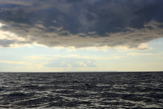 
at the bottom of the dark water, dark clouds at the top, in the middle of the bright horizon
