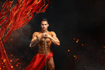 Artistic portrait of muscular male in red waving fabric.