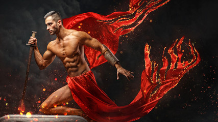 Artistic portrait of muscular male in red waving fabric.