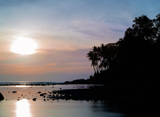 Fototapeta na wymiar Beautiful colorful sunset near the smal eaxotic island with palm