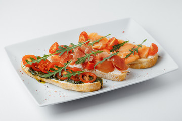 sandwiches with greenary, tomatoes, and meat on a white plate