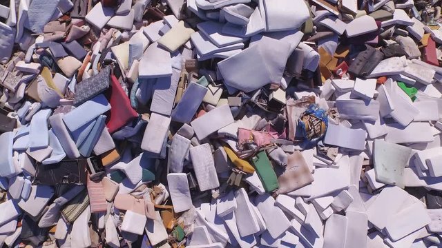 AERIAL: Big piles of old mattresses and sofas in the garbage dump