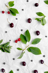 Cherries and cherry with leaves on a white parchment