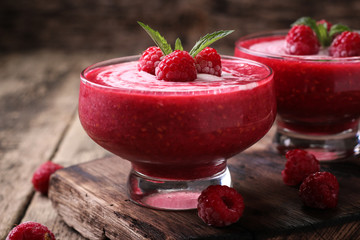 Pink raspberry smoothie with ice cream and mint on a rustic wood background