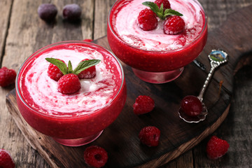 Pink raspberry smoothie with ice cream and mint on a rustic wood background