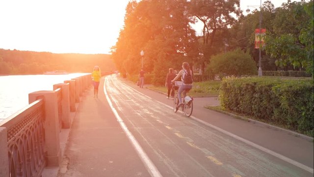 female runner running at sunset in city park.