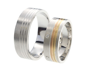 Two wedding rings standing next to each other isolated on white