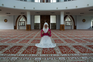 Muslim young woman praying in mosque