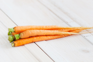 bunch of young carrots with  bow  twine on  wooden surface in  rustic style