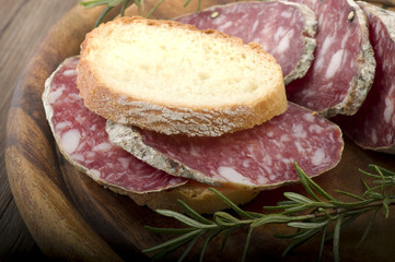 wooden cutting board with salami and bread
