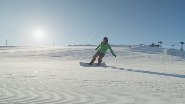CLOSE UP: Snowboarder carving on groomed snow in ski resort