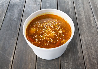 Asian red fish soup with sesame closeup at gray wood