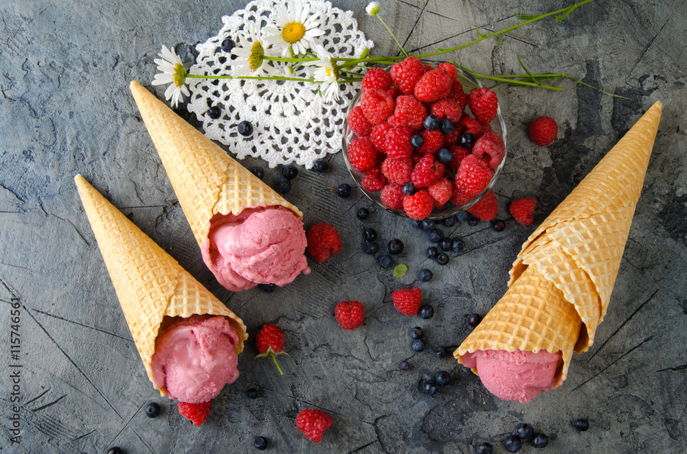 Poster raspberry ice cream with ice cream cones on stone table.