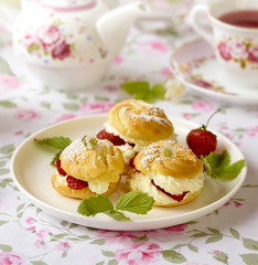 Cream puff cakes or profiterole filled with whipped cream, served with strawberries