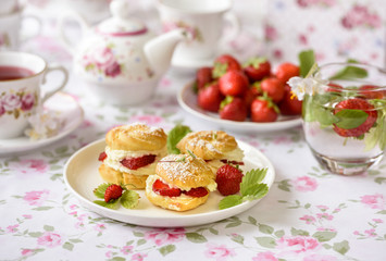 Cream puff cakes or profiterole filled with whipped cream, served with strawberries