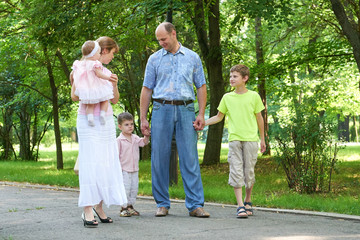 happy family walking in city park, group of five people, summer season, child and parent