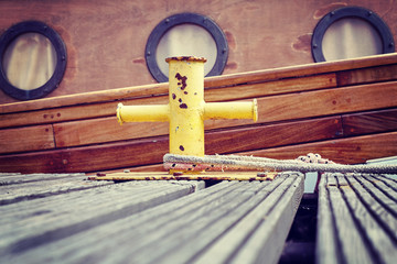 Vintage stylized wooden boat moored to bollard in marina, nautical background.