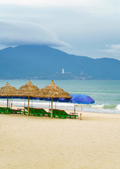 Palm shelter and umbrellas with sunbeds in China Beach