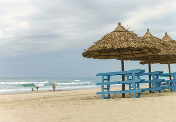 Palm shelters and tourists at China Beach of Da Nang
