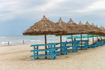Palm shelters and tourists in China Beach in Da Nang