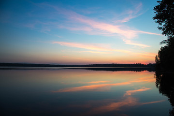Fototapeta premium Sunset on forest lake grass on the shore