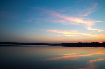 Sunset on forest lake grass on the shore