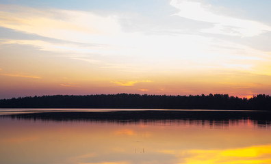 Fototapeta na wymiar Sunset on forest lake grass on the shore