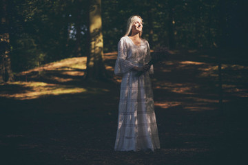 Fototapeta na wymiar Blonde bride catching sunlight in forest