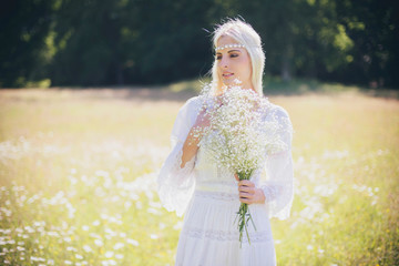 Fototapeta na wymiar Blonde bride in meadow with flowers