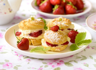 Cream puffs or profiterole filled with whipped cream,g served with strawberries