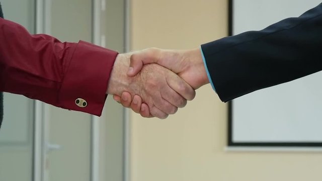 Closeup of business people shaking hands over a deal slow motion