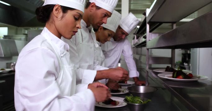Row of chefs garnishing dessert