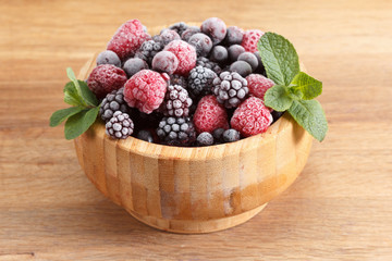 Frozen berries in wooden bowl, covered with ice