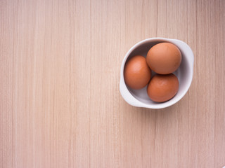 Egg in bowl on wood background. Top view