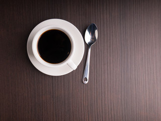 Black coffee cup on brown wood table with coffee bean
