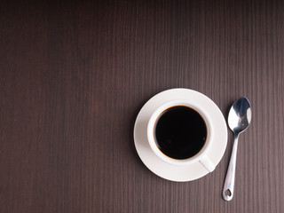 Black coffee cup on brown wood table with coffee bean