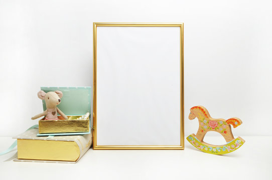 Gold frame mock-up, and white wall with toys.mouse, and mint book Place work