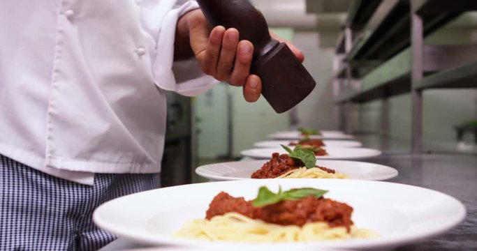 Chef seasoning spaghetti dinners with black pepper