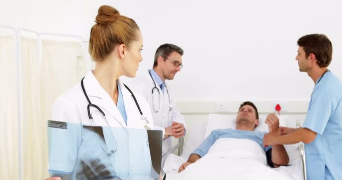 Doctors speaking with sick patient in bed while one checks xray