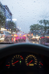 Car dashboard and wet windshield of a car in Bangkok traffic
