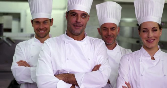 Four happy chefs looking at camera with arms crossed