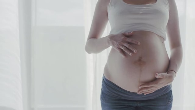 Pregnant woman touching her belly. 4K