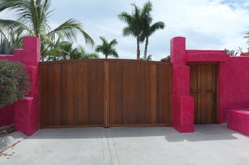 Wooden gate and door on bright pink wall