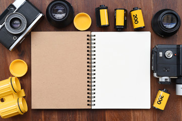 Blank notebook with photo film, pen and camera on wooden background