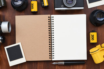 Blank notebook with photo film, photo frames and camera on wooden background