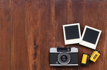 Photo film with photo frames and camera on wooden background