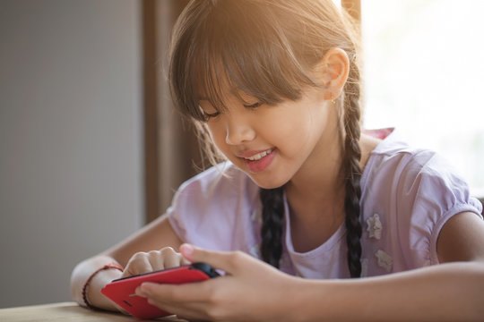 Happy Asian girl playing game on mobile phone