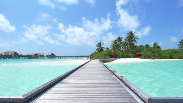 Wooden piers leading from water villas to exotic beach in Maldives